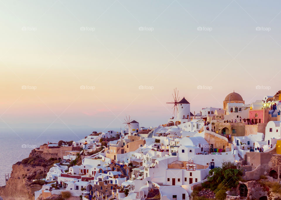 Santorini at sunset. Sunset at Ia town with famous landmark windmills and beautiful whitewashed houses on Santorini island, Mediterranean sea