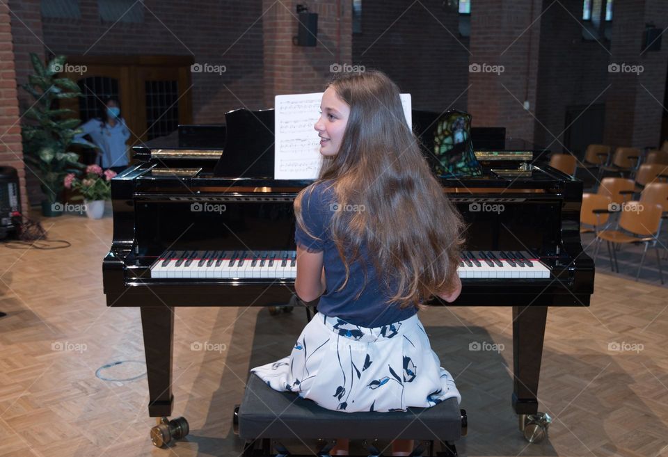 teenage girl playing the piano in the concert hall, hobby, playing music on the instrument

