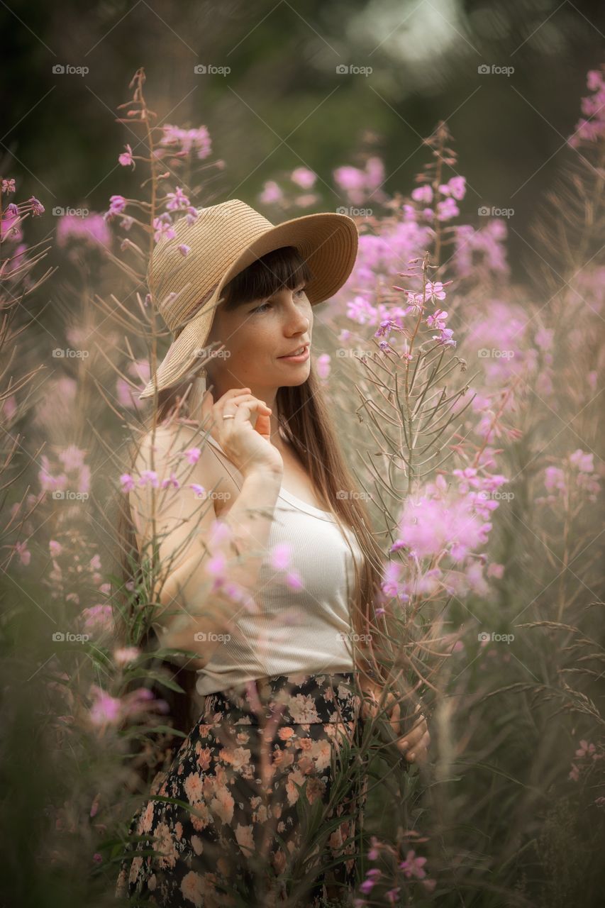 Beautiful young woman in a field of blossom flowers in boho style