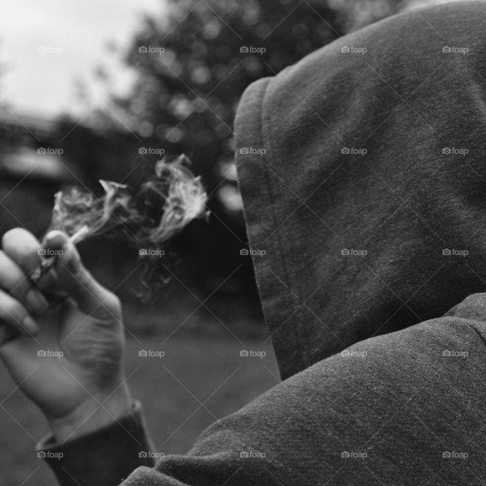 Mysterious person wearing a hoodie smoking