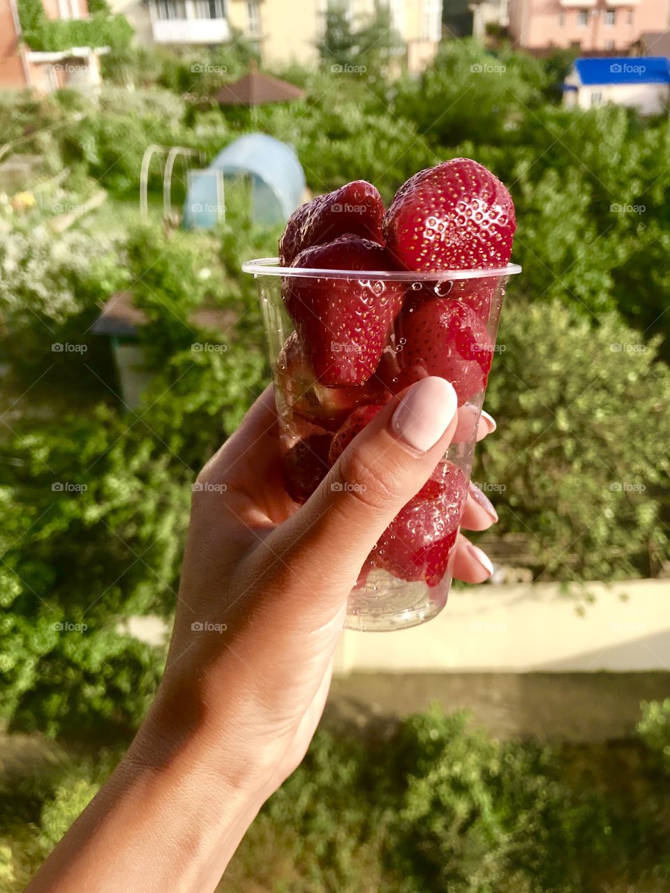 Delicious fresh red strawberries in a transparent glass on the hand of the girl, summer, sun, berries