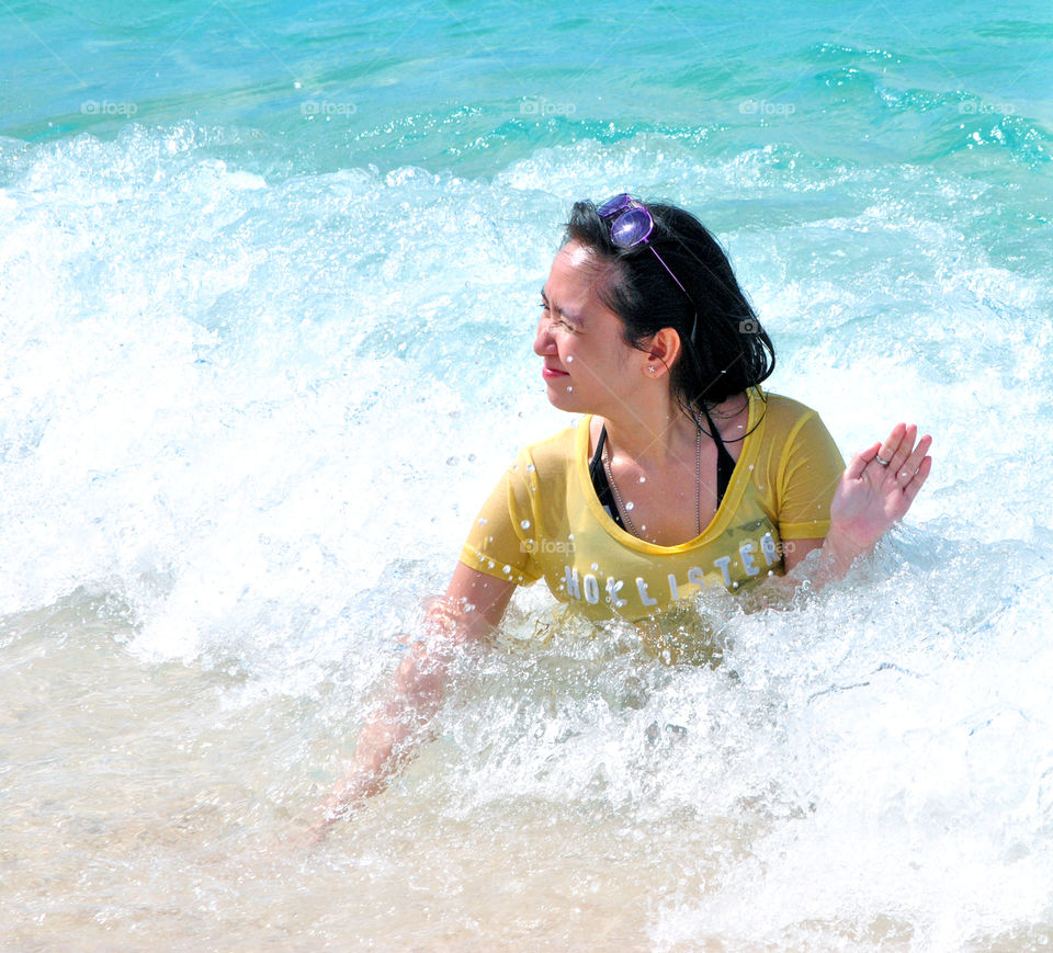 Girl having fun at the beach, playing along the waves at the seashore