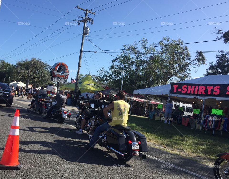 Motorcyclists in Daytona Beach and Ormond Beach Florida during Biketoberfest biker festival. Riding past street vendors, tents, bar, Iron Horse saloon. Honda, BMW motorbikes, trikes and 3-wheelers. 