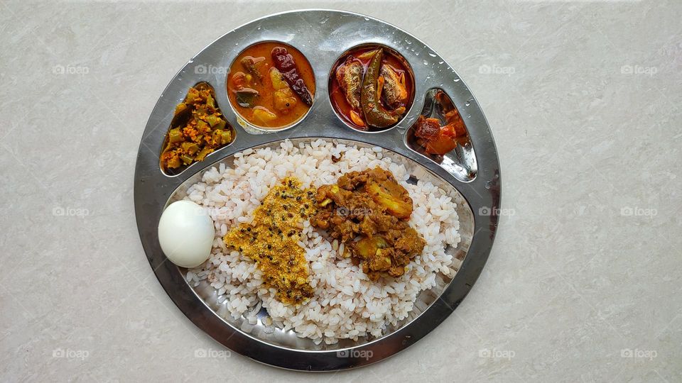 Indian rice meal which includes Sambar and fish curry, spicy curry from India, Indian vegetarian and non-vegetarian curry, food from India, Thoran(left end) and lemon pickle (right end)