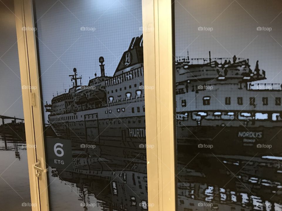 Picture of “Hurtigruten” (Norwegian ships) on a door inside a hotel in Bergen. The door is white, and has a 6. Floor sign on it. Picture is taken in Bergen, Norway.