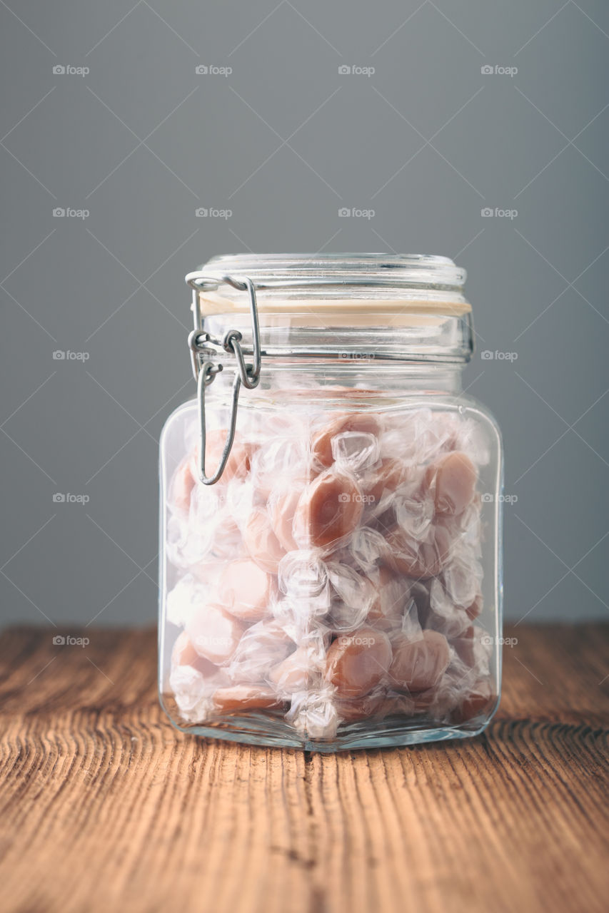 Jar filled with caramel milky candies on table