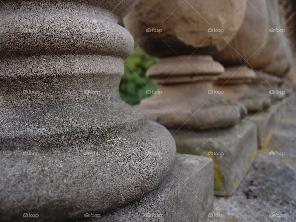 Old carved stone pillars decorate the side of a bridge. 