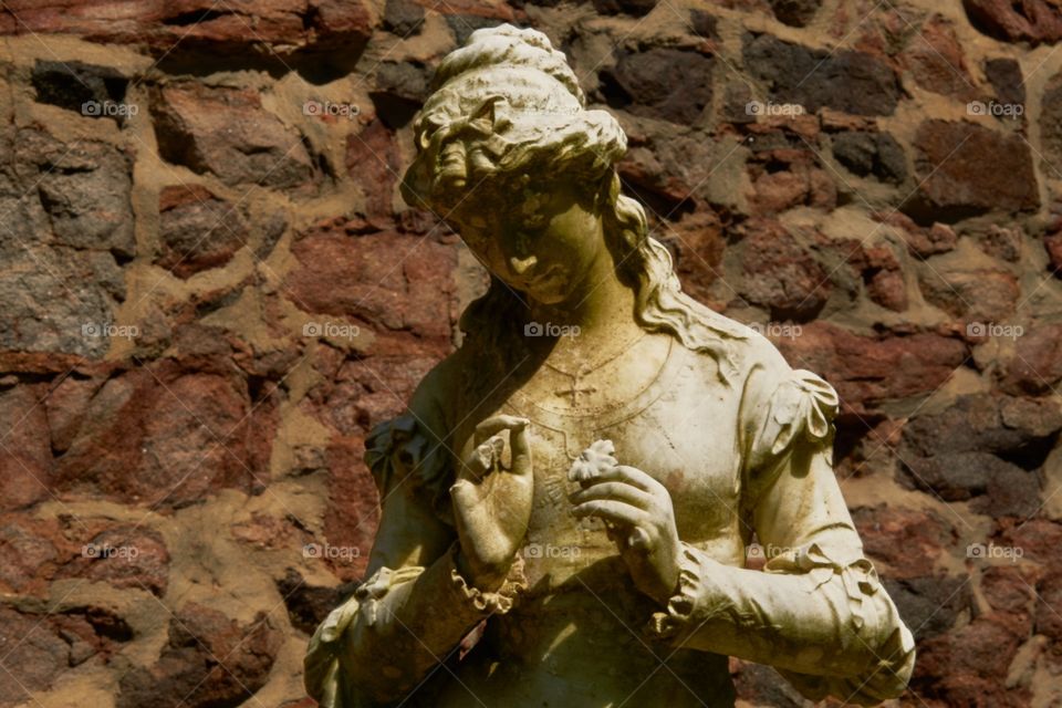 Close up of a statue of a woman in a brick background 