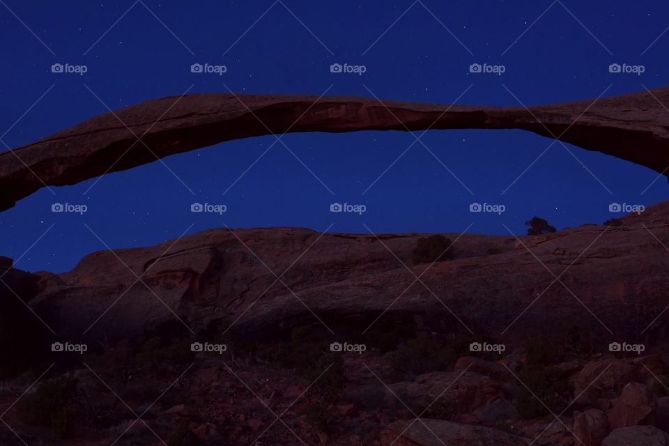 Arches National Park during dawn on a spring morning. Natural features and red slickrock make this scene surreal. Stars in a blue sky add something extra.