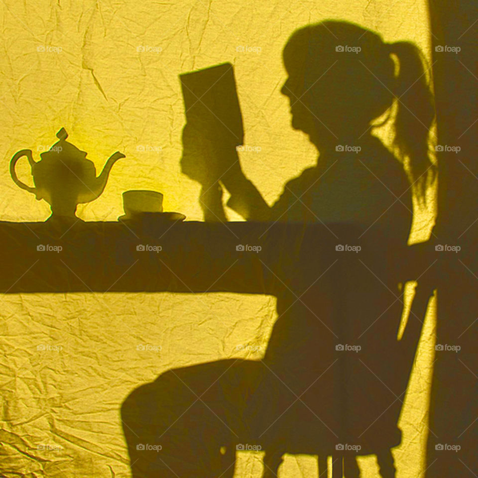 Woman enjoying a relaxing cup of tea while reading a book, yellow and grey