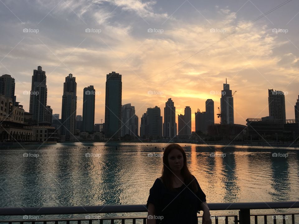 Woman standing in front of city building during sunset