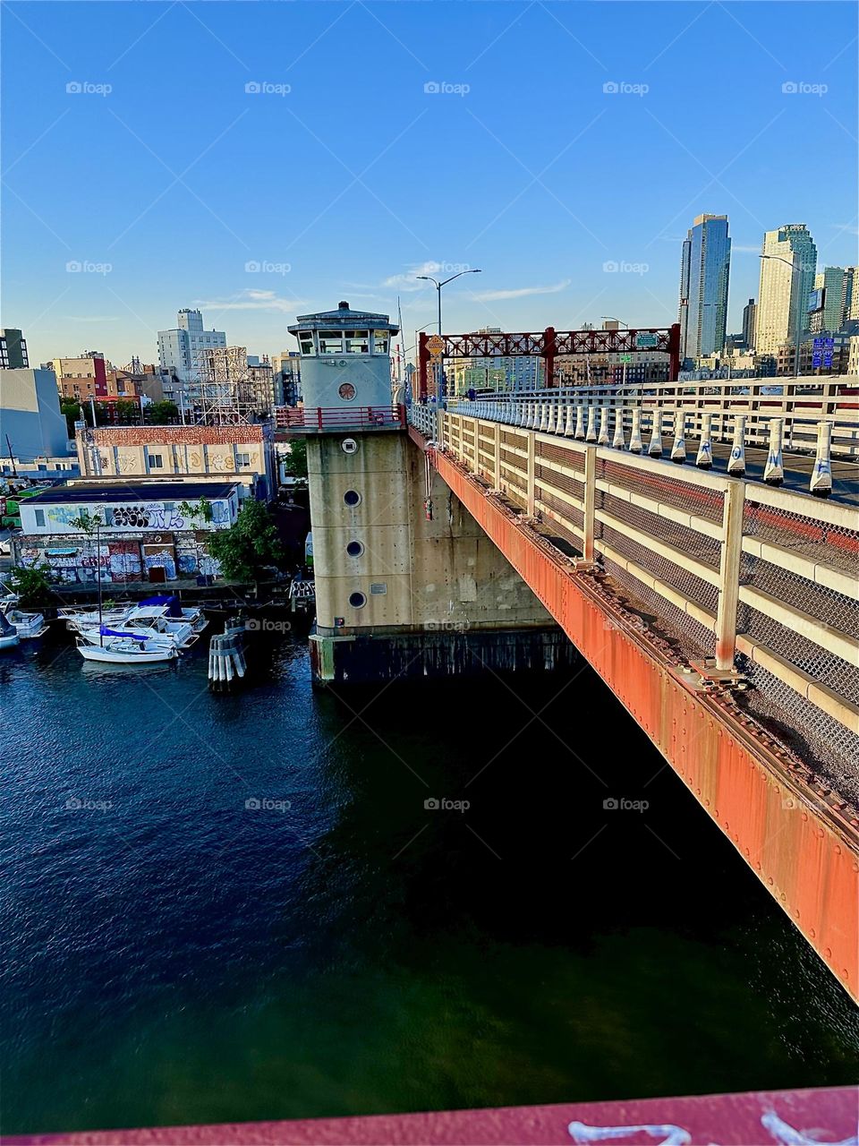The streamlined design of the metal railing of the “Pulaski Bridge” at “Newtown Creek” extends smoothly from “Greenpoint”, Brooklyn to the LIC shore and the watchtower cabin. 2024. Hypnotic Productions