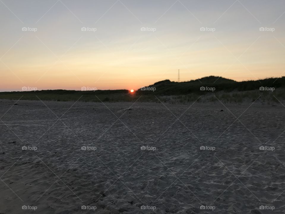Picture of sun in crescent of sand dunes.