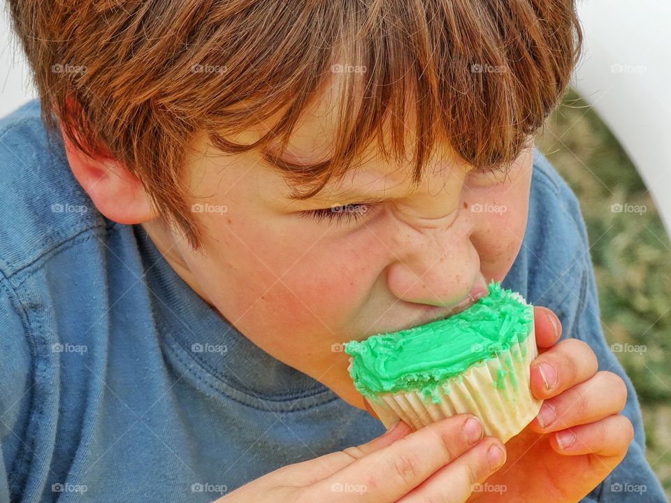 Boy Eating A Cupcake. Young Boy Eating A Cupcake With Green Frosting