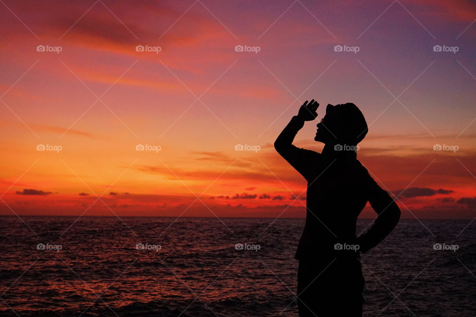The silhoutte of a girl with sunset sky as the backgroung