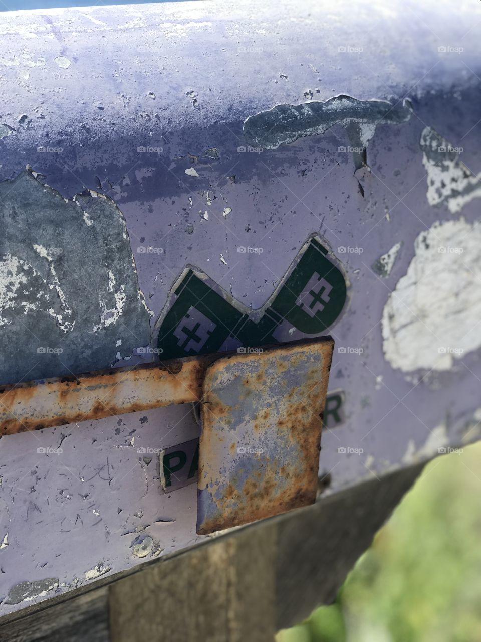 A closeup of the beauty of aging. A mailbox shows its battle wounds while standing the test of time against nature and the elements. 