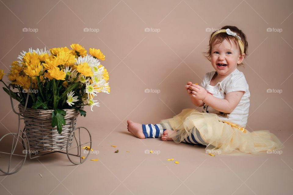 Happy little girl sitting near basket of flowers