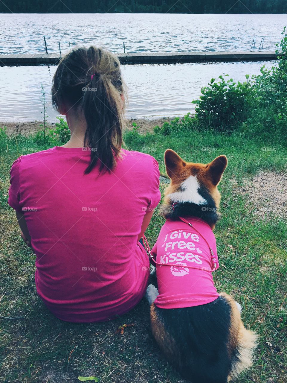 Cute dog and a girl dressed in pink looking out over the lake