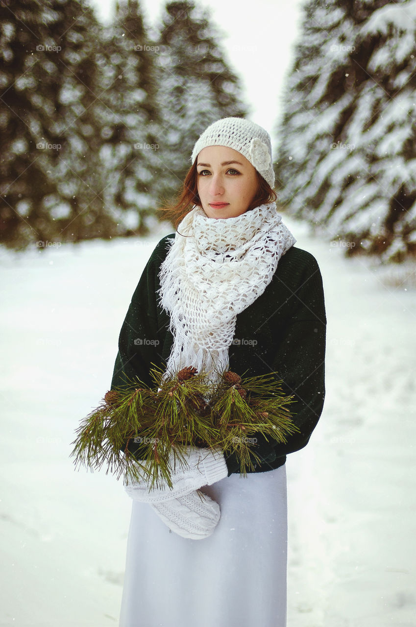 Winter portrait of young redhead woman in green sweater in snowcovered winter park.