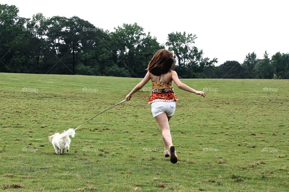 Life with pets. 

A cute young girl running with her dog across the field.