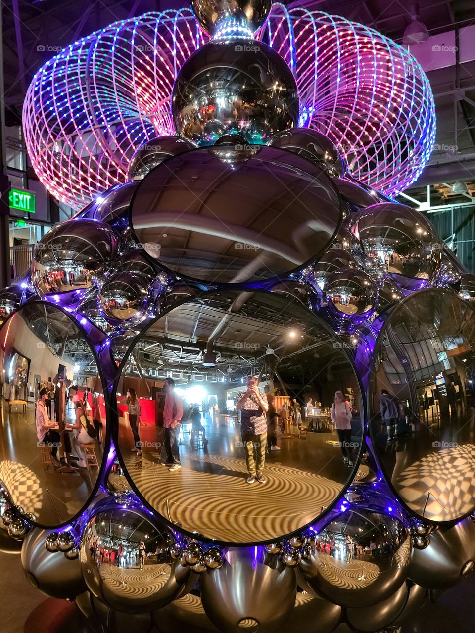 Mirrored sculpture reflecting beautiful array of colorful lights hanging from the ceiling 