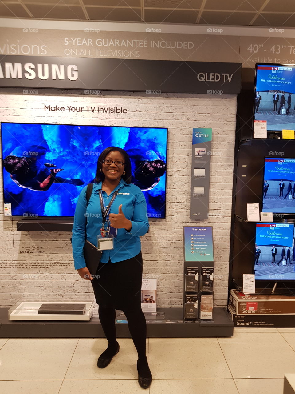 Antonia posing in front of the Samsung QLED television wall mounted with soundbar