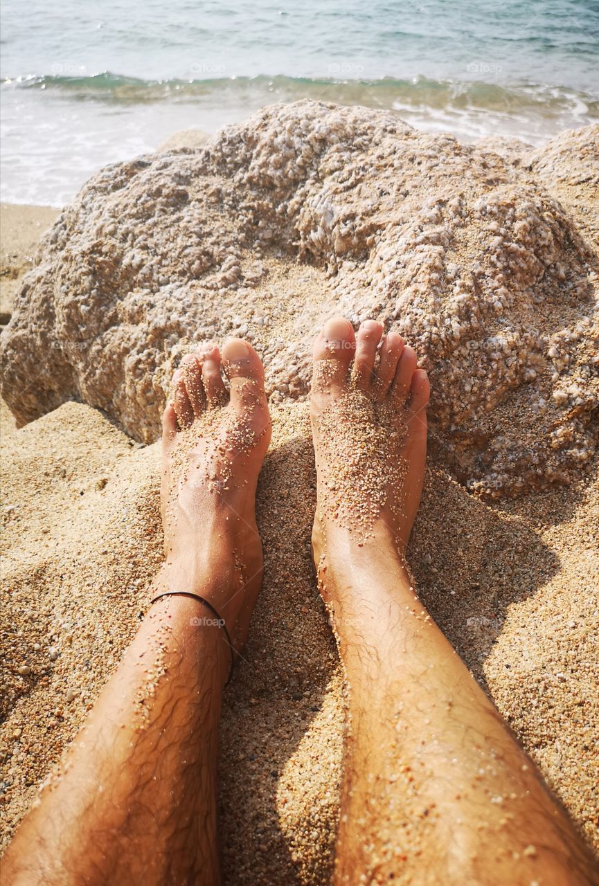 male feet on beach covered by sand