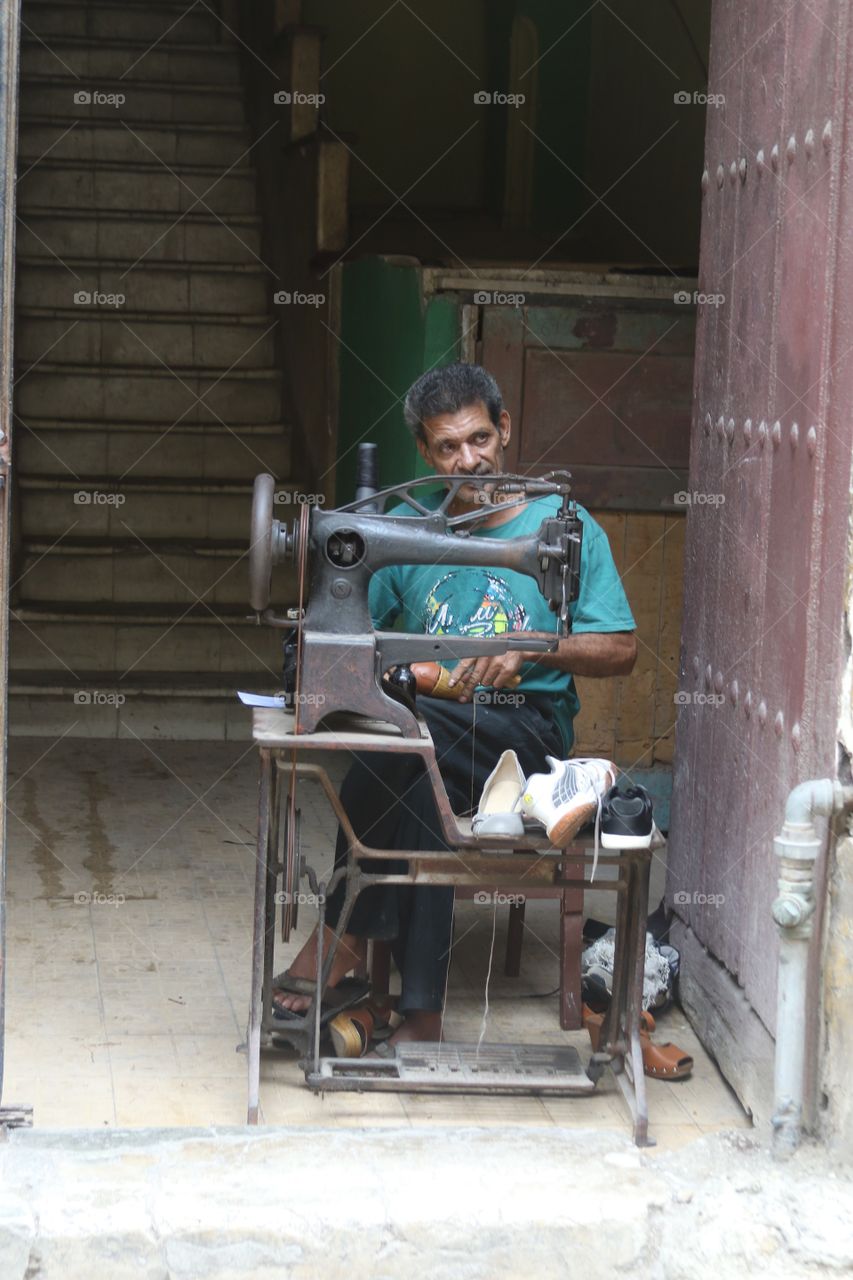 Man repairing shoes on street in Havana