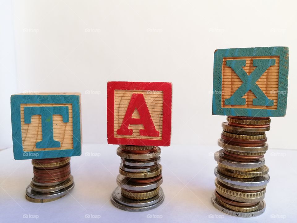 Written: "TAX" with wooden cubes and coins