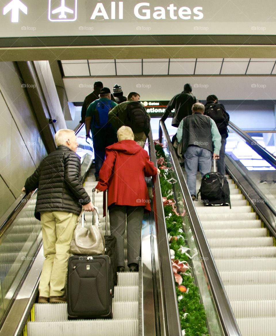 Holiday travel, family going up escalator to get to their gate and board the plane