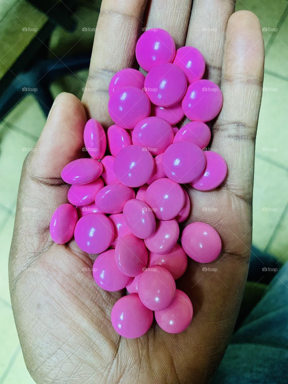 A hand of pink Ibuprofen tablets. This round film coated tablets are used for pain management.