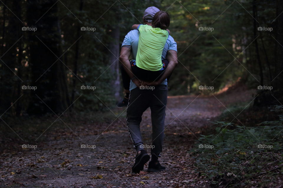 Father Back Carrying His Son Through Forest