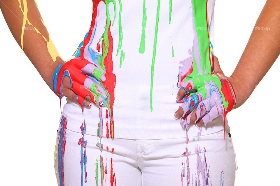 Girl dressed in white soaked in multi color paint dripping