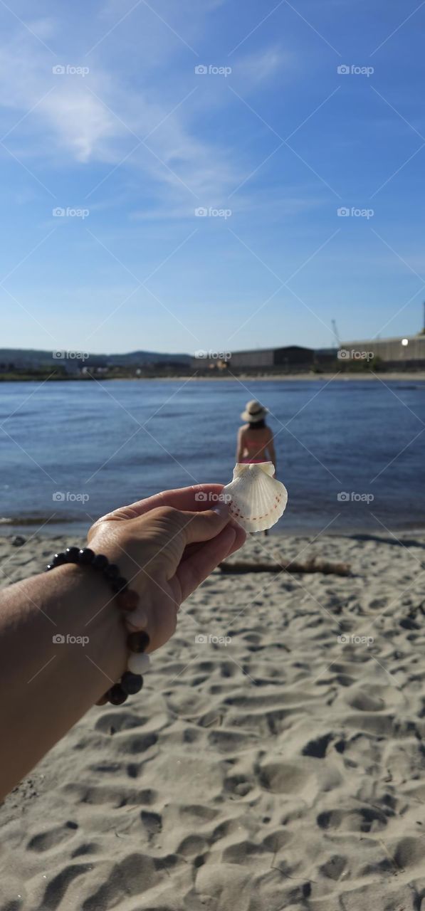 A tiny little woman at the beach . With a funny Shell dress. Isent it funny . 
Looks funny