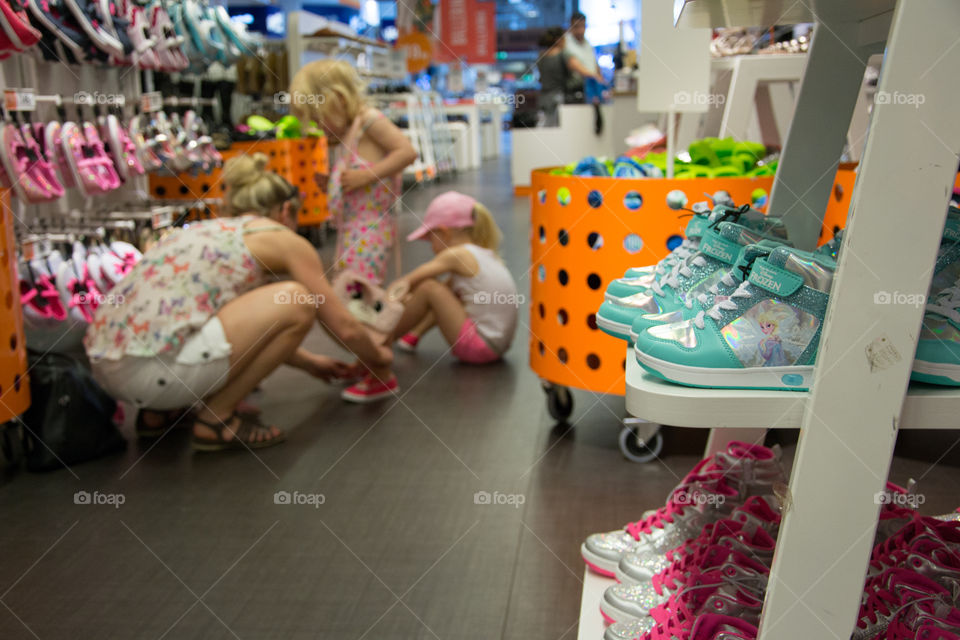 Mother is shopping new shoes for her young girls in a shopping mall in Mobilia Malmö Sweden.