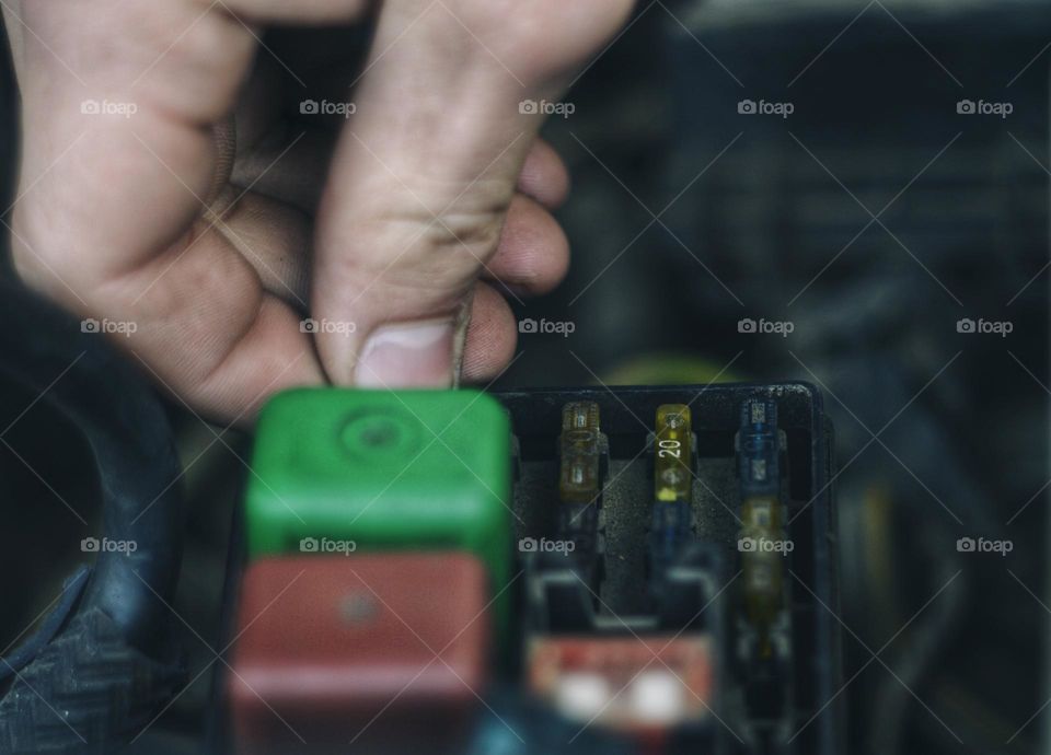 replacement of old damaged fuses in the car. in the photo, a person’s hand has several fuses and relays