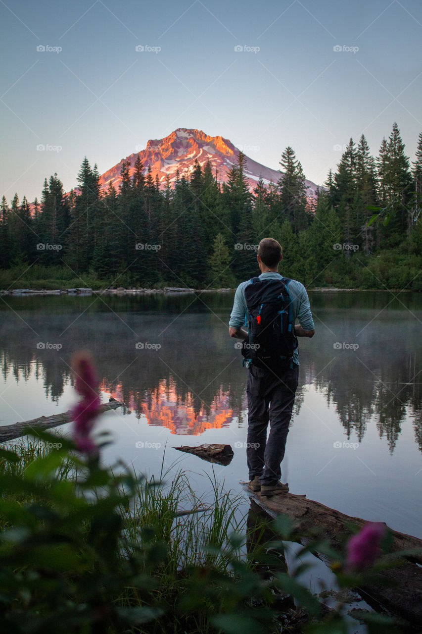 Hiker enjoying the peaceful sunrise at a serene lake 