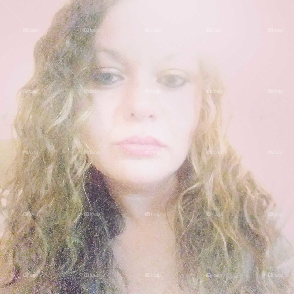 Beautiful, confident, white female with naturally curly hair lookin how she feels. Perhaps...over it.