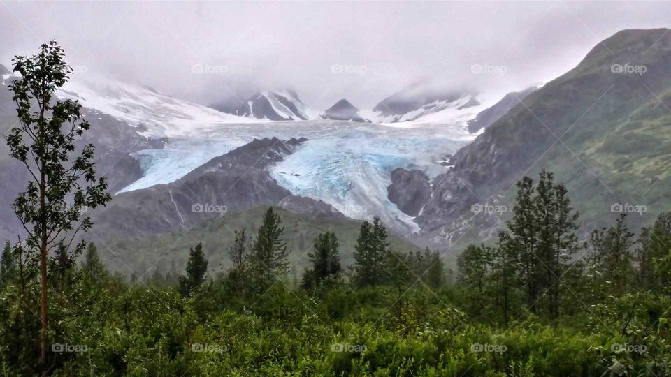 Fascinating flow of a glacier into the green summer valley below.