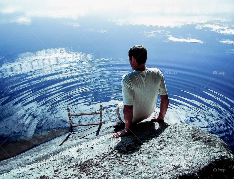 Rear view of person sitting on rock