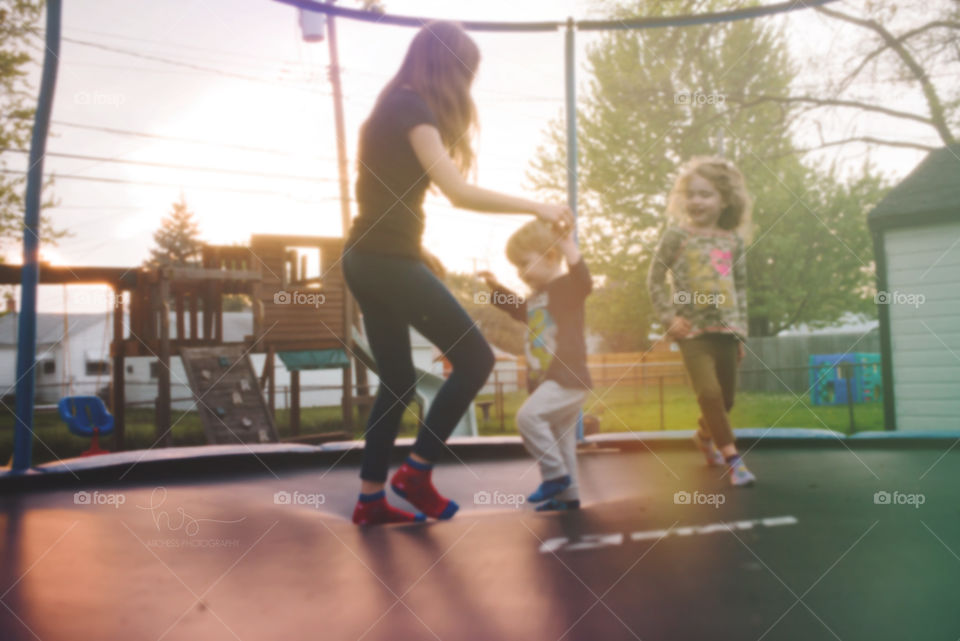 Kids playing on trampoline in sunset