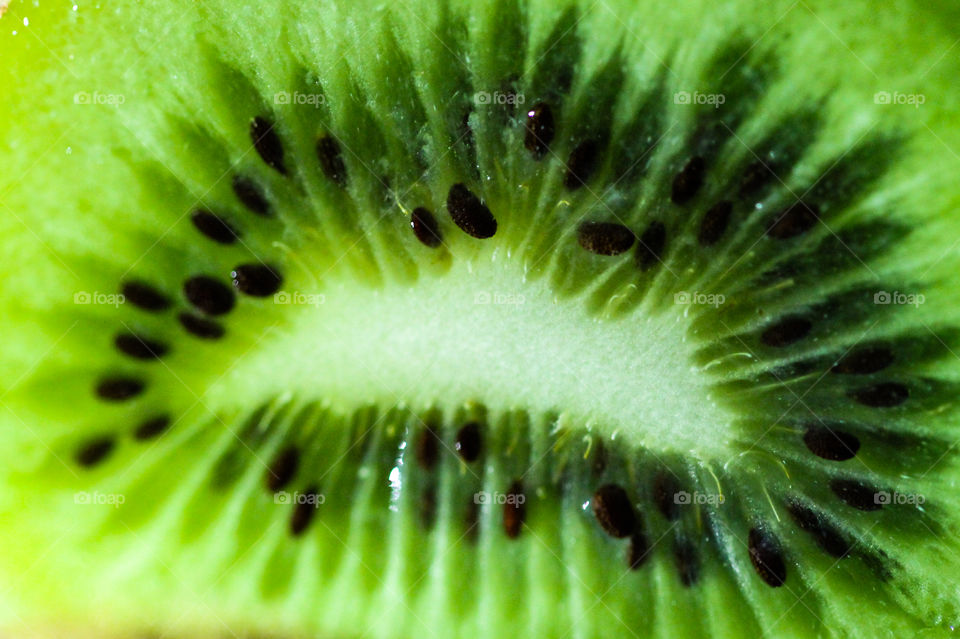 Macro shot of the inside of a ripe kiwi fruit. A Kiwi fruit is a berry because it is a single fleshy fruit without a stone & contains seeds. The Kiwi grows on a vine & is also called a Chinese gooseberry or the Chinese name of origin, mihoutau.