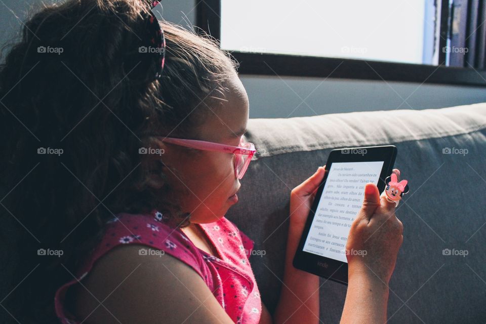 Little girl reading a children's book on Kindle