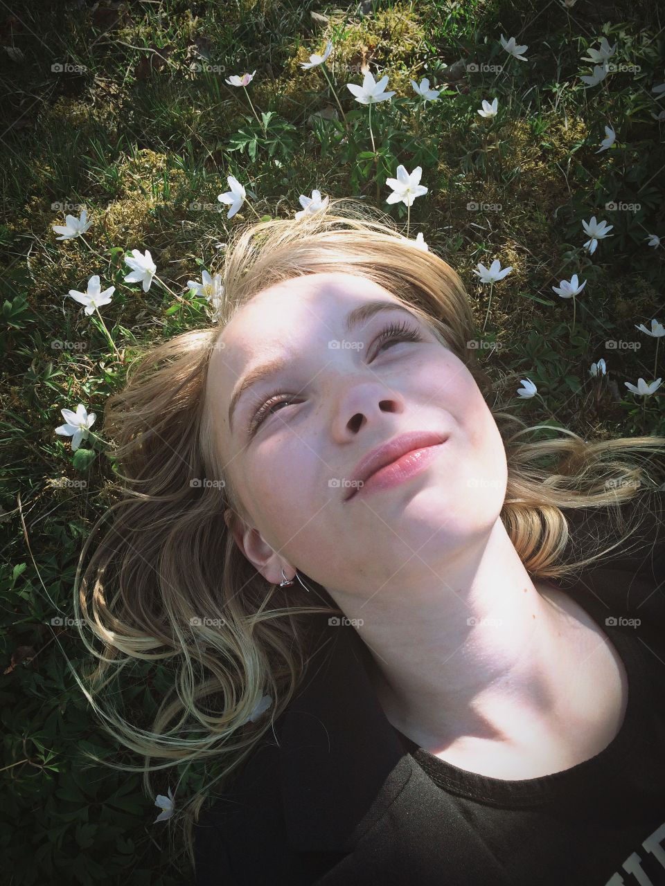 Spring joy. Girl laying in the grass among anemones