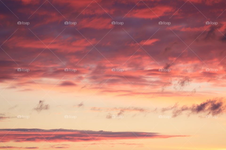 A canopy of brilliantly colored clouds in a pastel-yellow sky