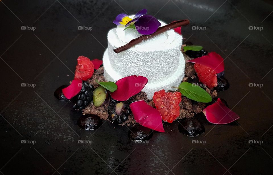 Close-up photo of delicious fancy desert served on black plate in restaurant