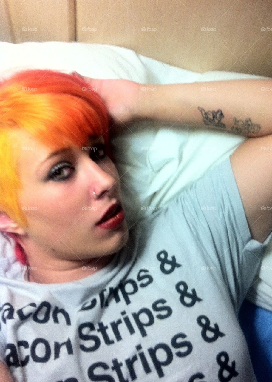 Bacon strips and cool hair. . Woman with tattoos and unusual hair lying on a bed. 