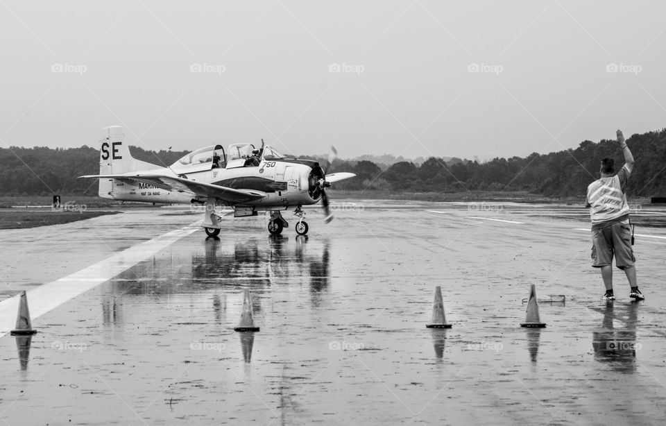 Airplane being parked on runway with hand signals in bnw