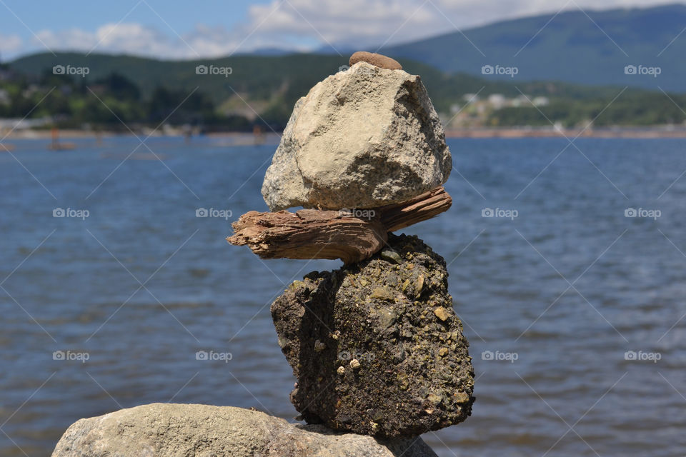 Stone stack overlooking ocean and facing toward west coast mountains near Vancouver
