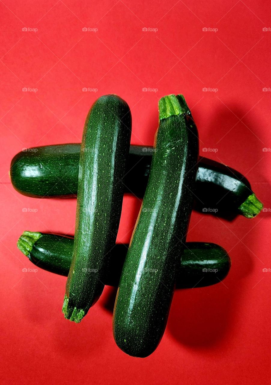Red and green complementary colours flatlay made with zucchini placed as a hashtag on a red surface